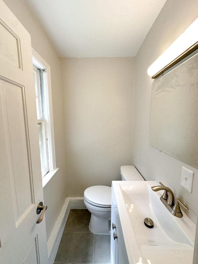 half bath with vanity, tile patterned floors, toilet, and baseboards