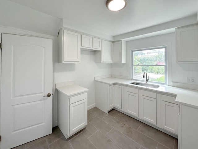 kitchen featuring light countertops, white cabinets, a sink, and light tile patterned flooring