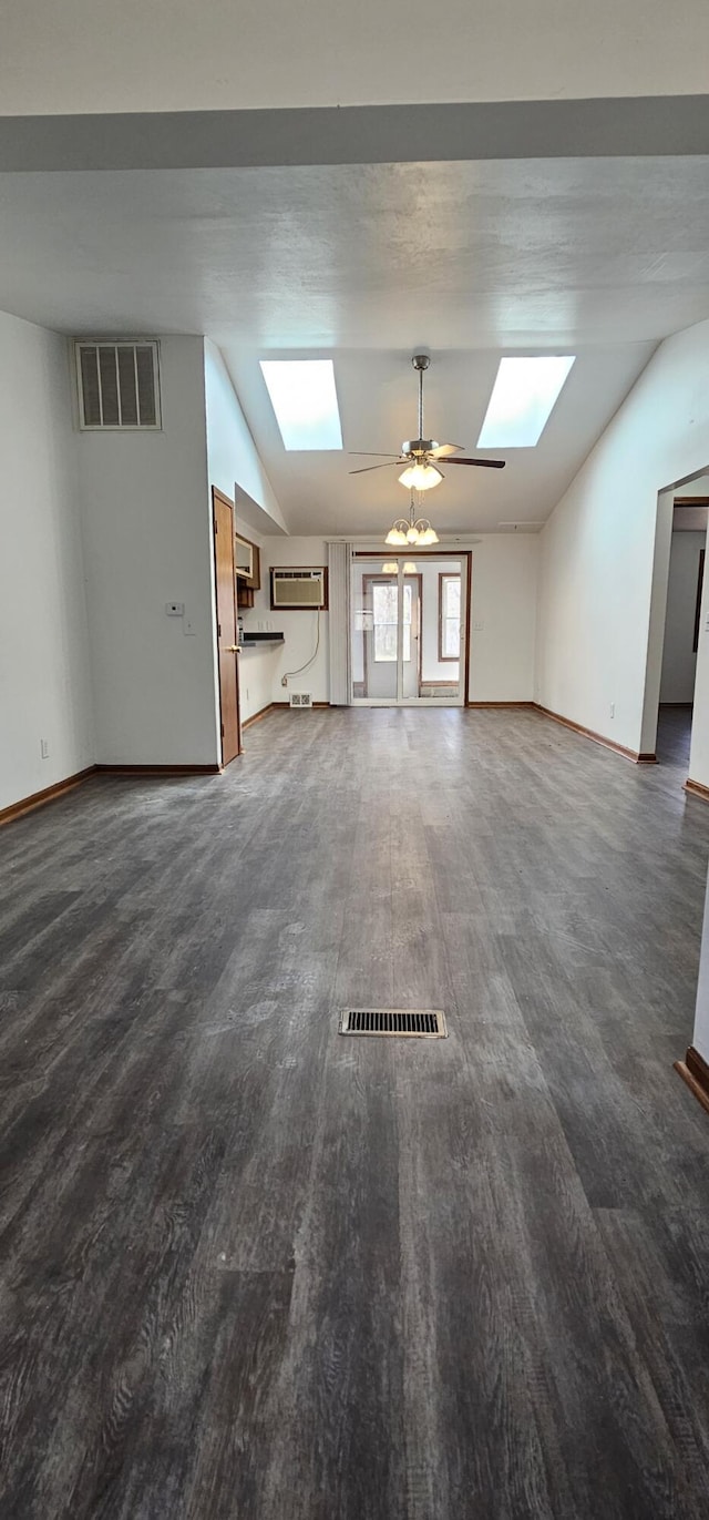 unfurnished living room featuring vaulted ceiling with skylight, dark wood-type flooring, visible vents, and baseboards