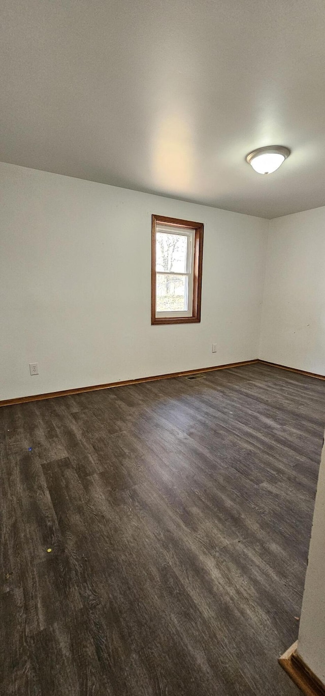 unfurnished room with dark wood-type flooring and baseboards