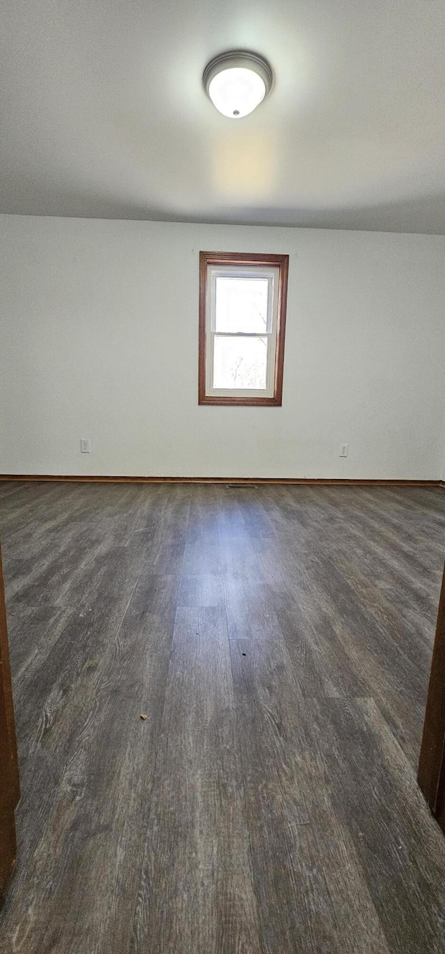 unfurnished room with baseboards and wood finished floors