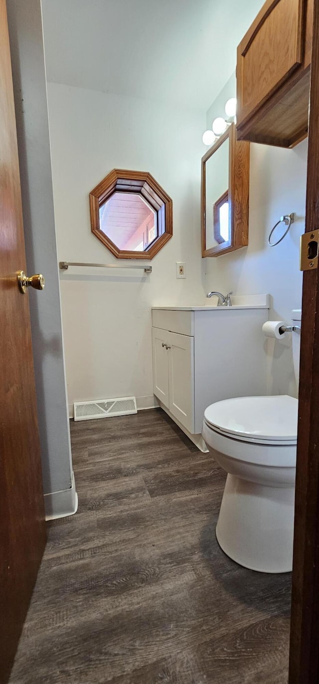 bathroom featuring visible vents, toilet, vanity, wood finished floors, and baseboards