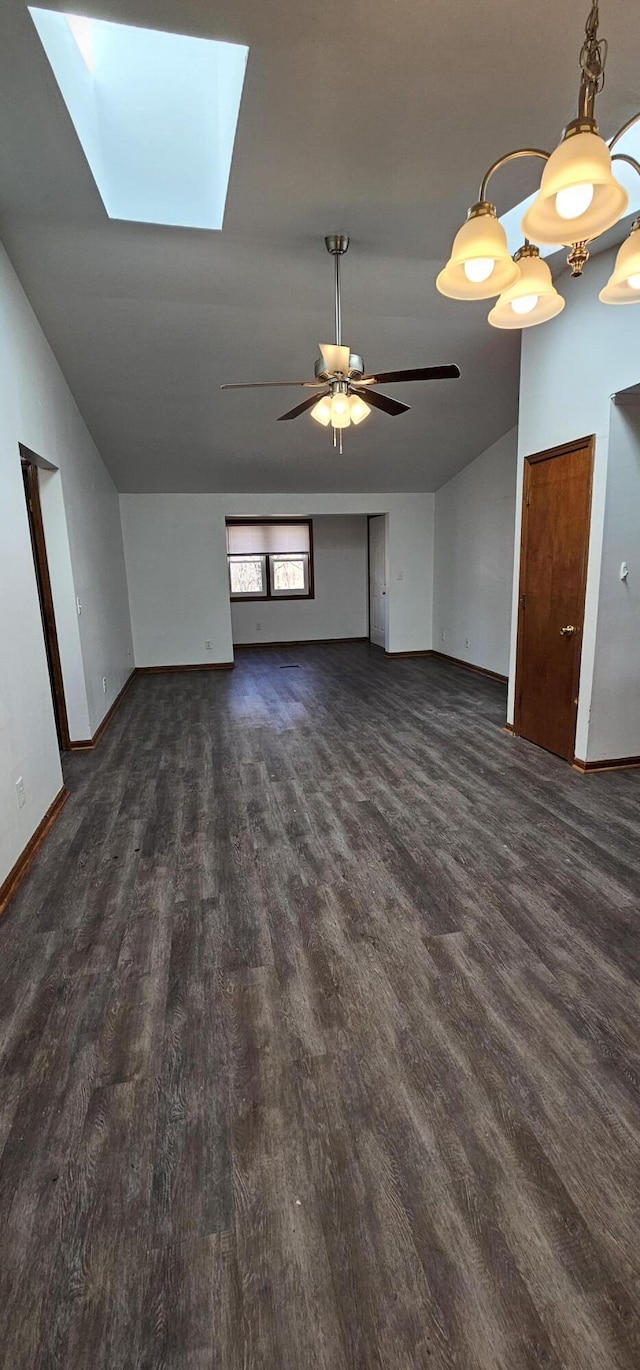 unfurnished living room with lofted ceiling with skylight, dark wood finished floors, and baseboards