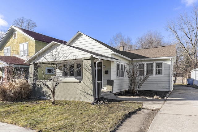 bungalow-style house featuring roof with shingles, driveway, and a chimney