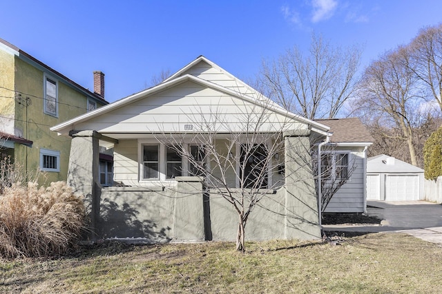 view of side of home with covered porch, a detached garage, and an outdoor structure