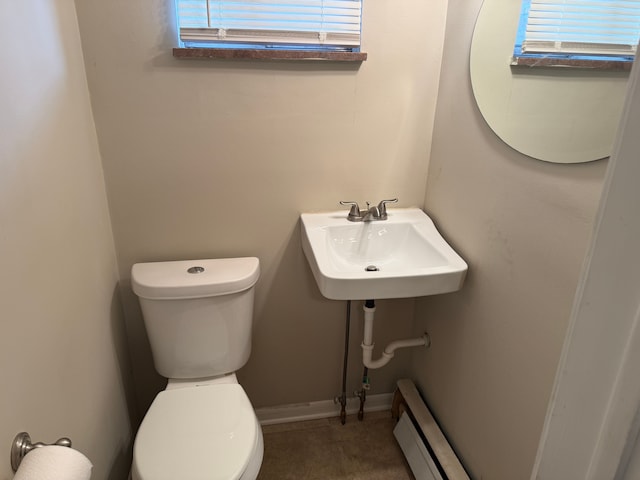 half bathroom featuring a sink, a baseboard radiator, toilet, and tile patterned floors