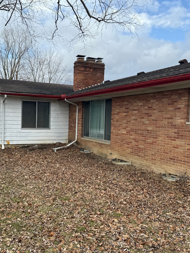rear view of property featuring brick siding and a chimney