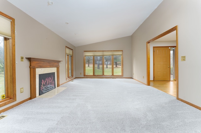 unfurnished living room featuring lofted ceiling, carpet floors, a premium fireplace, visible vents, and baseboards