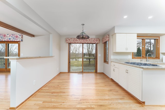 kitchen with light wood-style floors, pendant lighting, white cabinets, and baseboards