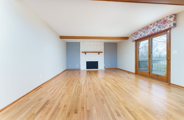 unfurnished living room with baseboards, beam ceiling, and light wood-style floors