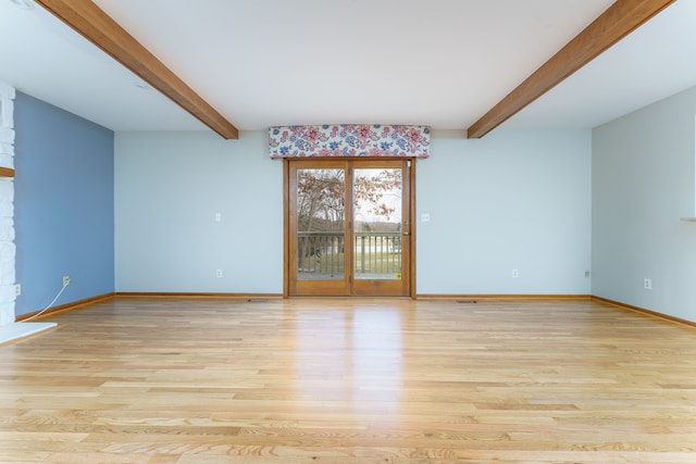 spare room with baseboards, beam ceiling, and light wood-style floors