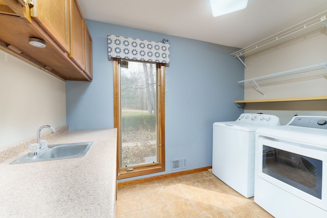 clothes washing area featuring light tile patterned floors, a sink, visible vents, washer and dryer, and cabinet space