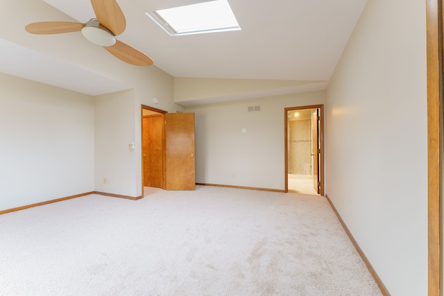 empty room with baseboards, lofted ceiling with skylight, visible vents, and light colored carpet