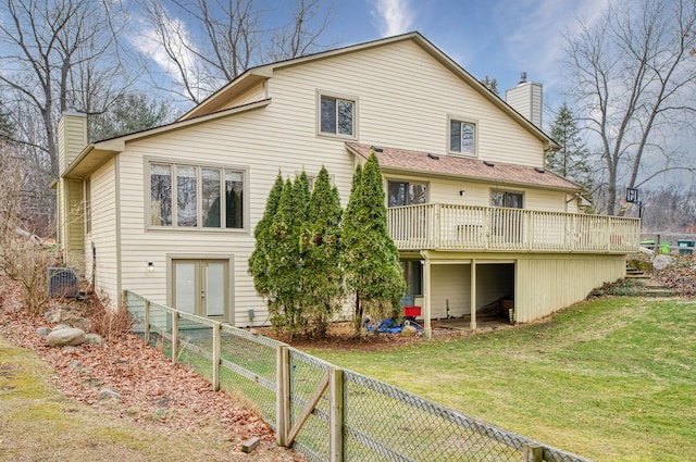 back of property with a yard, a chimney, a fenced backyard, and a wooden deck