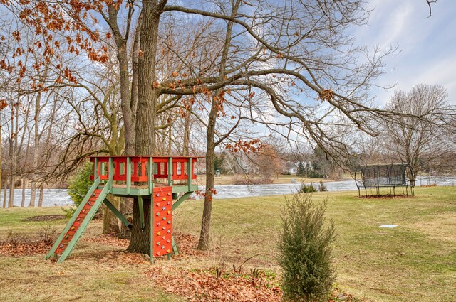 view of yard with playground community, a trampoline, and a water view