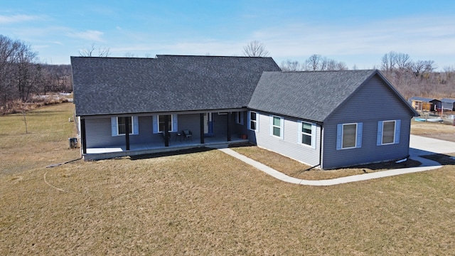 view of front of home with roof with shingles and a front yard