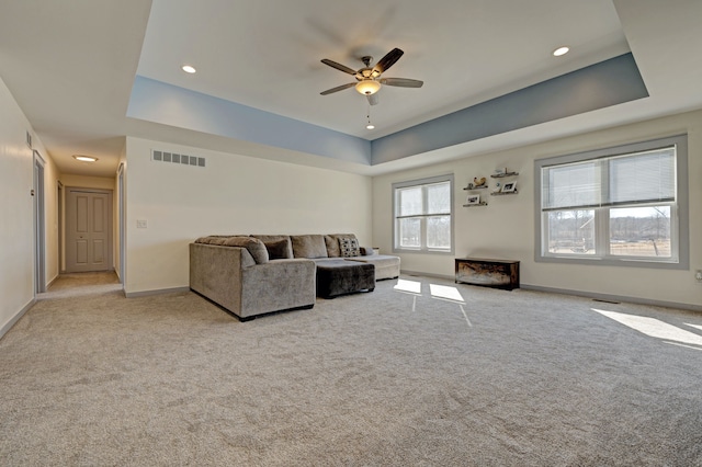 unfurnished living room with carpet, visible vents, a tray ceiling, and baseboards