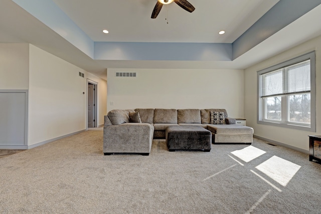 carpeted living room with recessed lighting, a raised ceiling, visible vents, and baseboards