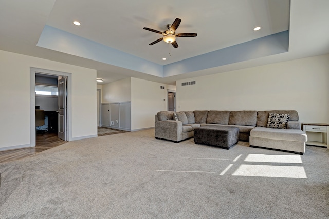 carpeted living room featuring recessed lighting, a ceiling fan, visible vents, baseboards, and a tray ceiling