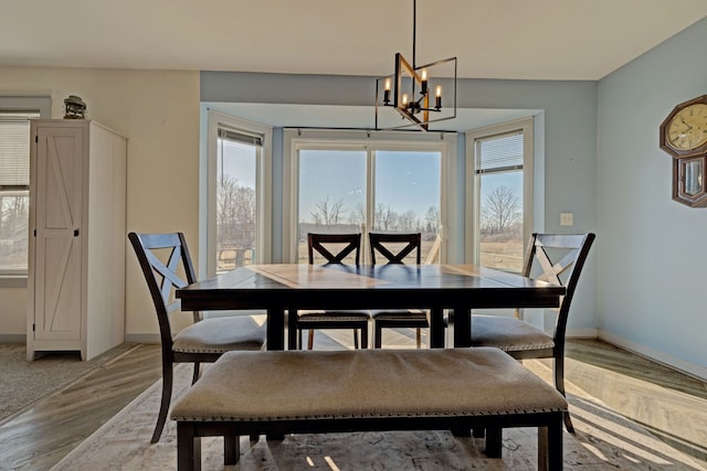 dining area featuring plenty of natural light, light wood-style flooring, baseboards, and an inviting chandelier