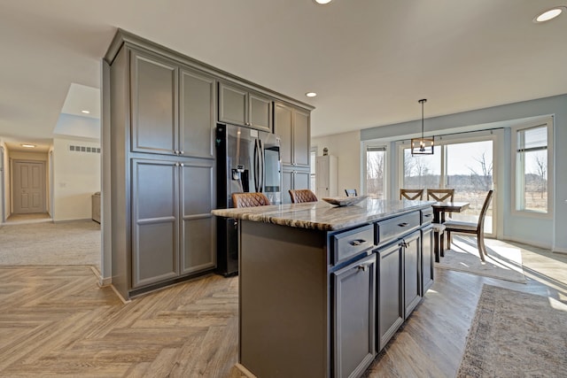 kitchen with a center island, visible vents, recessed lighting, and light stone countertops