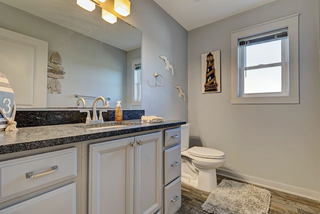 bathroom with baseboards, vanity, toilet, and wood finished floors