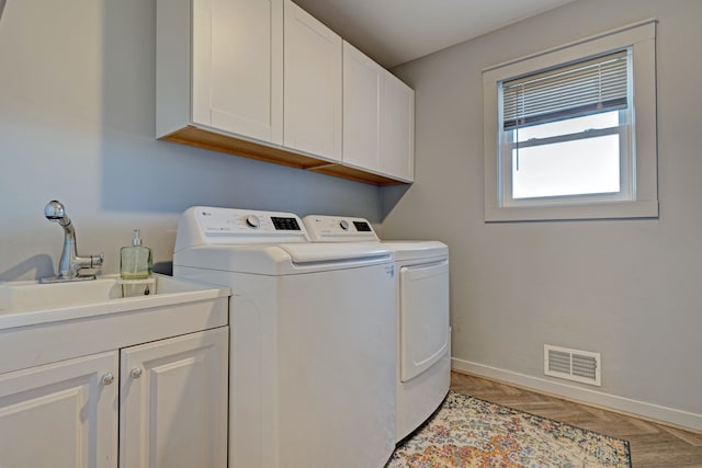 laundry room featuring cabinet space, visible vents, a sink, washer and dryer, and baseboards