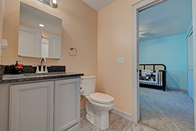 bathroom featuring baseboards, ceiling fan, vanity, and toilet