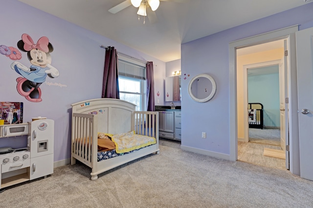 carpeted bedroom with a sink, a ceiling fan, and baseboards