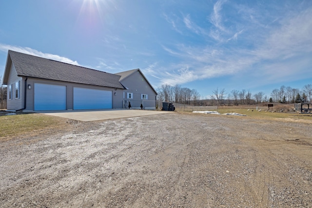 view of home's exterior with dirt driveway and a shingled roof