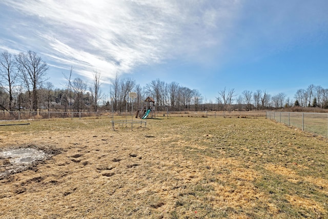 view of yard with a playground, fence, and a rural view