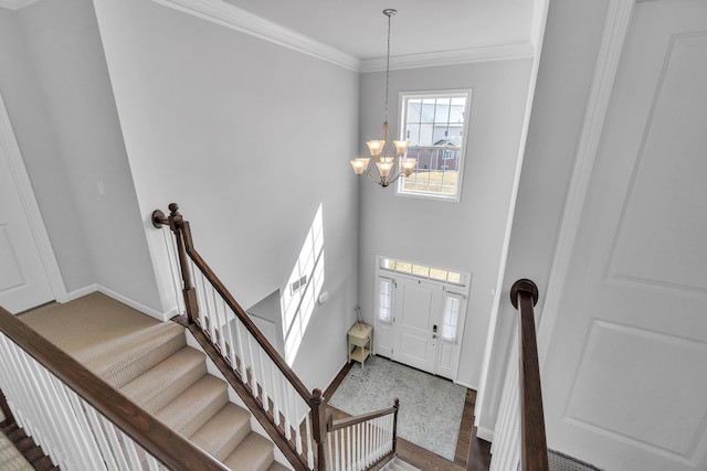 entrance foyer with a high ceiling, baseboards, stairs, ornamental molding, and an inviting chandelier