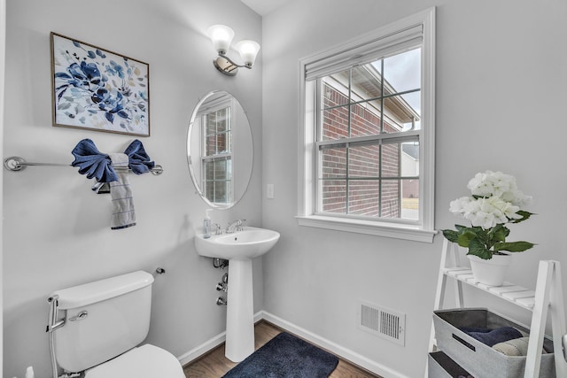 bathroom with a healthy amount of sunlight, baseboards, visible vents, and toilet