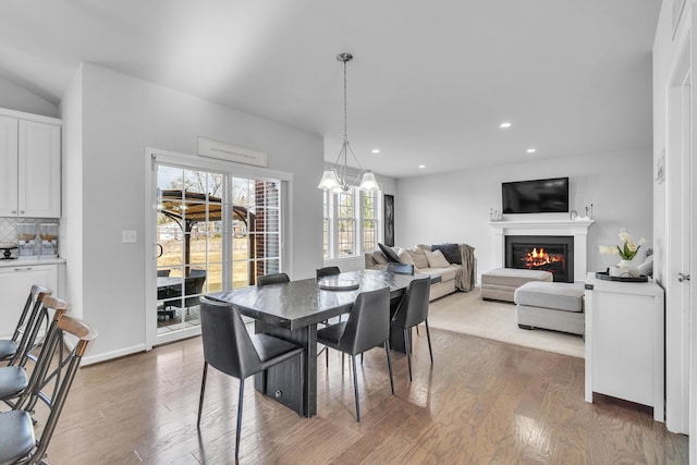 dining room with a glass covered fireplace, baseboards, recessed lighting, and wood finished floors