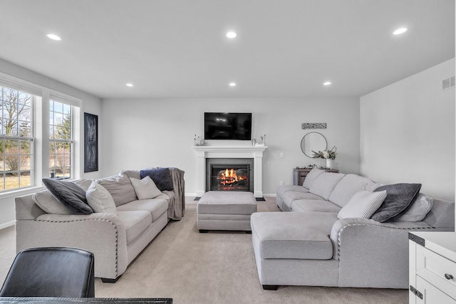 living room featuring visible vents, baseboards, light colored carpet, a glass covered fireplace, and recessed lighting