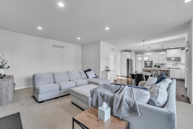 living room featuring recessed lighting, visible vents, a notable chandelier, and baseboards