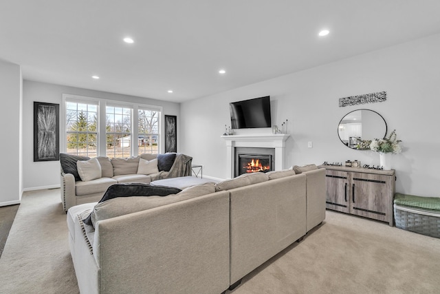 living area with a glass covered fireplace, light colored carpet, baseboards, and recessed lighting