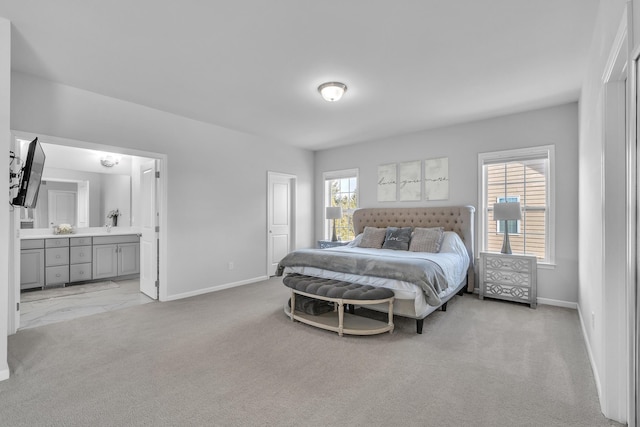 bedroom with light colored carpet, connected bathroom, and baseboards