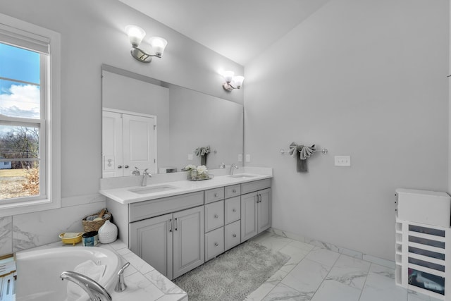 bathroom with lofted ceiling, marble finish floor, a sink, and double vanity