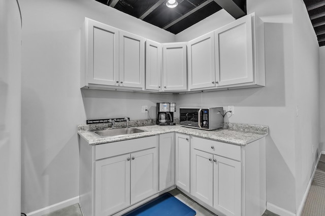 interior space featuring white cabinetry, a sink, and baseboards