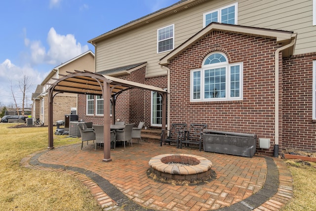 back of property featuring brick siding, a patio, a lawn, central AC unit, and a fire pit