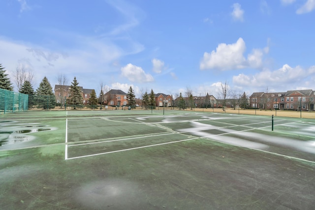 view of tennis court featuring a residential view and fence