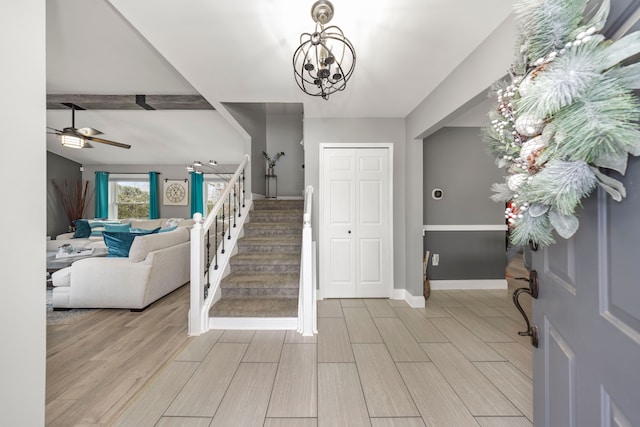 entryway with wood finish floors, stairway, baseboards, and ceiling fan with notable chandelier