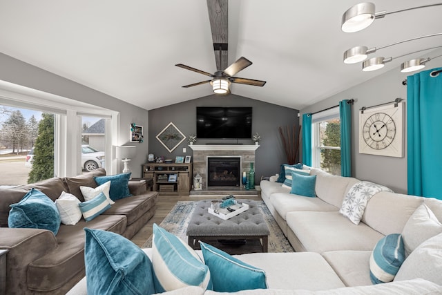 living area featuring vaulted ceiling, ceiling fan, wood finished floors, and a glass covered fireplace