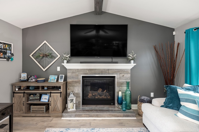 living room with lofted ceiling with beams, wood finished floors, and a glass covered fireplace