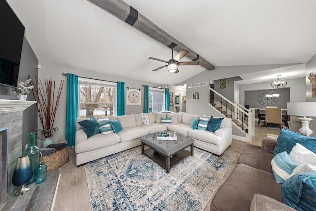 living area with lofted ceiling with beams, a fireplace, wood finished floors, visible vents, and stairs