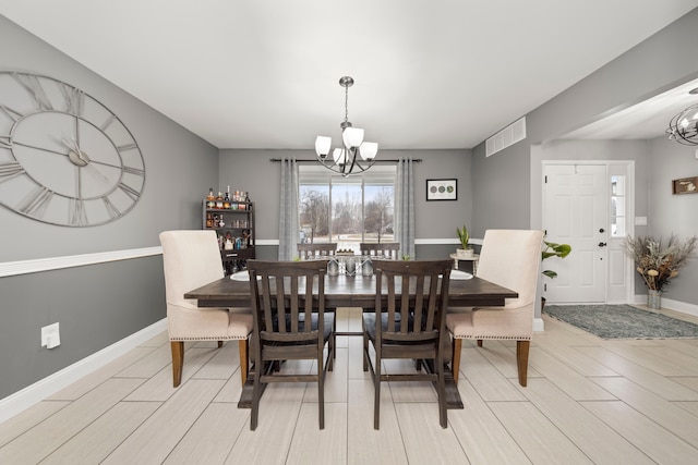 dining space featuring an inviting chandelier, baseboards, and visible vents