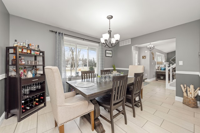 dining room featuring baseboards, stairs, visible vents, and an inviting chandelier