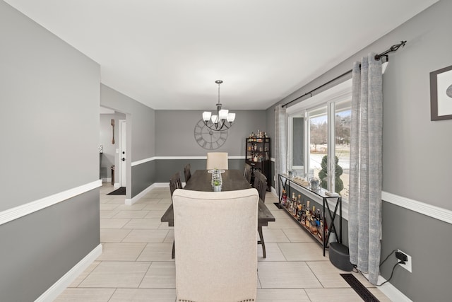 dining area featuring baseboards, light tile patterned floors, and a notable chandelier