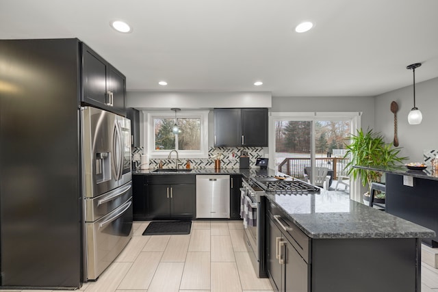 kitchen with decorative backsplash, appliances with stainless steel finishes, dark stone countertops, a peninsula, and a sink